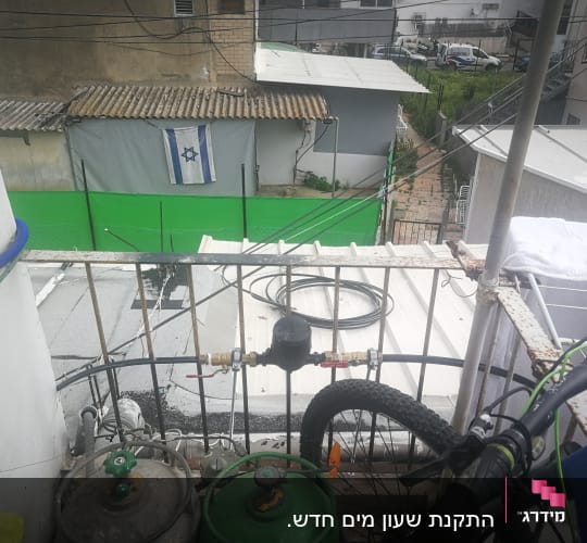צינור מים כחול מחובר למיכל גז על מרפסת